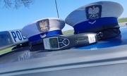 dwie czapki policyjne leżą na masce radiowozu obok alkotestera