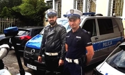 dwaj policjanci stoją na policyjnym parkingu obok motocykla i radiowozów
