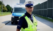 policjant ruchu drogowego stoi na drodze w tle radiowóz policyjny
