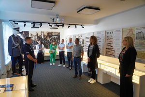 Osoby słuchające policjanta w pomieszczeniu izby Pamięci KWP w Bydgoszczy