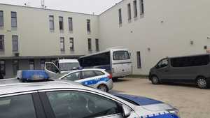 radiowozy, autobus i bus straży granicznej pod budynkiem Komendy Powiatowej Policji w Krapkowicach