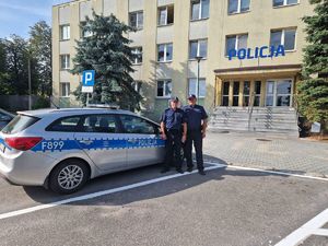 Policjanci stojący przy radiowozie na tle Komendy Powiatowej Policji w Pabianicach