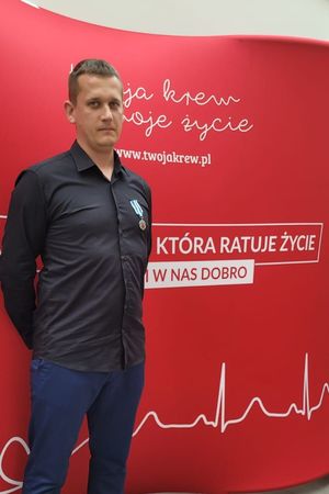 sierżant sztabowy Kamil Niedziałek z odznaczeniem, na tle baneru twoja krew, moje życie