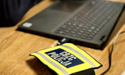 Laptop na biurku, obok opaska z napisem CBZC Policja.