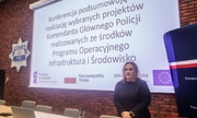 kobieta stojąca na tle ekranu, na którym wyświetlany jest napis Konferencja podsumowująca realizację projektów Komendanta Głównego Policji realizowanych ze środków Programu Operacyjnego Infrastruktura i Środowisko
