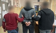 zatrzymany mężczyzna zakuty w kajdanki z dwoma policjantami