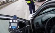 Policjant trzyma ręczny miernik prędkości i pokazuje wyświetlacz kierowcy osobówki