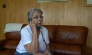 Starsza kobieta siedzi na kanapie i rozmawia przez telefon