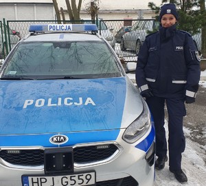 Policjantka stoi obok radiowozu w zimowej scenerii