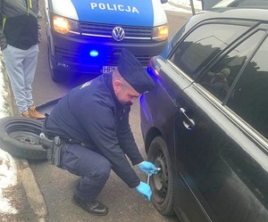 policjant w trakcie wymiany koła w samochodzie