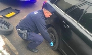 policjant w trakcie wymieniania koła w samochodzie