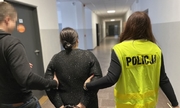policjant i policjantka prowadzą zatrzymaną kobietę zakutą w kajdanki