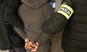 zatrzymany w kajdankach prowadzony przez dwóch policjantów
