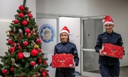Dwie policjantki z paczkami w dłoniach przy choince świątecznej