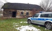 radiowóz stoi przy starym drewnianym domu