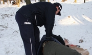 policjant pomaga mężczyźnie leżącemu na śniegu