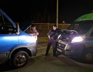 Policjant odpina kable rozruchowe po uruchomieniu drugiego pojazdu
