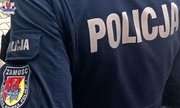odwrócony tyłem policjant z naszywką loga Policji na ramieniu