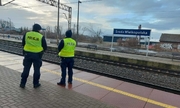 Dwóch umundurowanych policjantów patrolujących perony kolejowe.