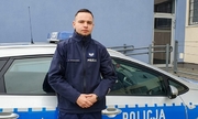 policjant stoi przy radiowozie policyjnym