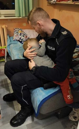 policjant z dzieckiem na rękach, które było pozostawione bez opieki