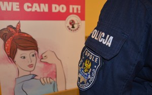 policjantka stojąca przy banerze z grafika kobiety i opisem w języku angielskim tłumaczonym na język polski o treści: możemy wszystko