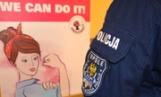 policjantka stojąca przy banerze z grafika kobiety i opisem w języku angielskim tłumaczonym na język polski o treści: możemy wszystko