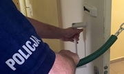 fragment ramienia policjanta zamykającego drzwi do celi, na rękawku koszulki napis policja