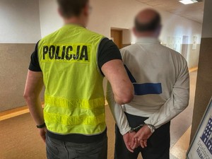 policjant z zatrzymanym mężczyzną zakutym w kajdanki
