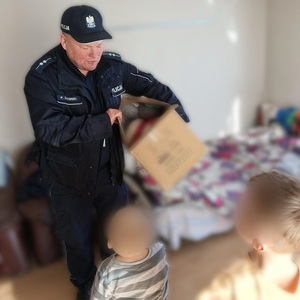 policjant wysypuje zabawki z kartonu na podłogę w domu