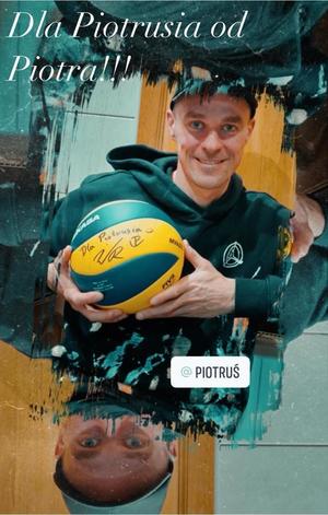 zdjęcie Piotra Żyły. Trzyma w rękach podpisaną przez siebie piłkę do siatkówki