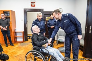 Chłopak na wózku inwalidzkim wita się z komendantem policji