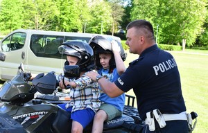 policjant w umundurowaniu służbowym i dwójka dzieci siedząca na quadzie