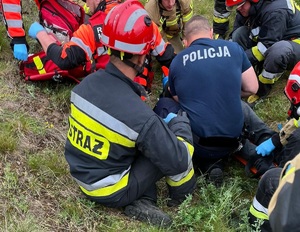 policjant i strażacy w trakcie udzielania pomocy poszkodowanemu