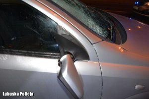 Samochód osobowy z rozbita przednią szybą  i uszkodzonym lusterkiem na miejscu zdarzenia drogowego w porze nocnej