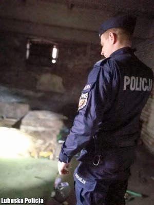Policjant sprawdza czy nie ma osób bezdomnych w opuszczonych pomieszczeniach