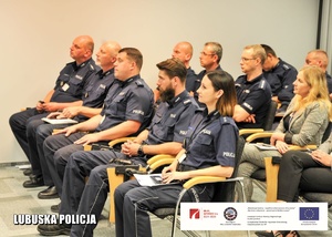 Policjanci siedzący na sali konferencyjnej.