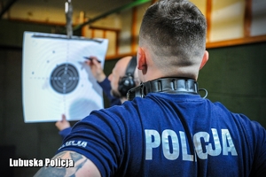 policjant liczy przestrzeliny w tarczy
