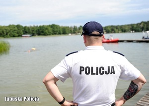 Policjant obserwuje ćwiczenia ratownicze na jeziorze.
