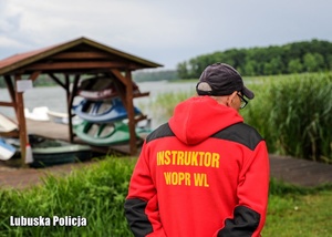 Ratownik wodny podczas szkolenia ratowniczego stoi nad brzegiem jeziora.