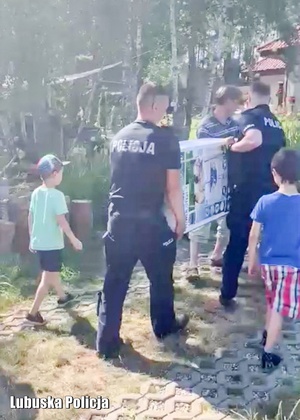 Policjanci wspólnie z mężczyzną przenoszą karton z basenem ogrodowym.