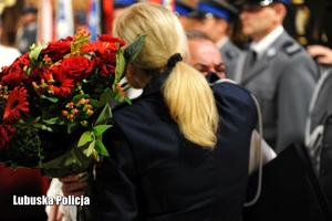 Policjantka wręcza kwiaty duchownemu.