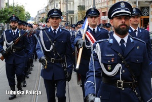 Kompania honorowa policjantów idzie ulicą.