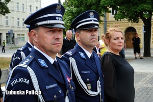 Policjanci stojący w szeregu, obok nich kobieta.