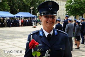 Policjantka z różą uśmiecha się do zdjęcia.