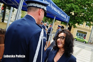 Policjant odbiera gratulacje od kobiety.