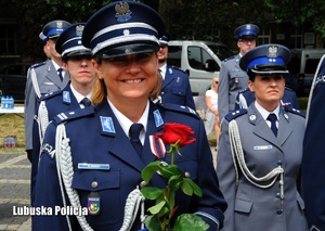 Policjantka z różą uśmiecha się do zdjęcia.