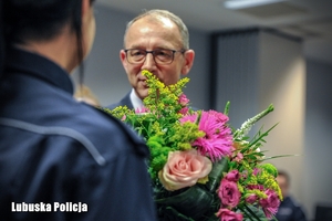Mężczyzna przekazuję kwiaty policjantce