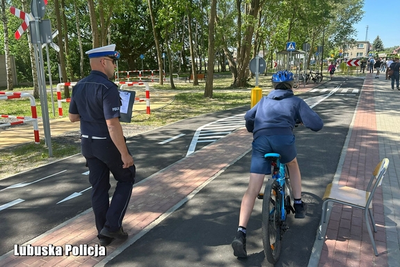 policjant obok rowerzysty jadącego po miasteczku ruchu drogowego.