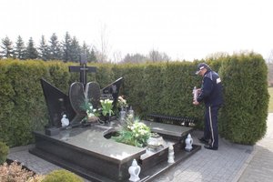 Komendant w Pabianicach stawia zapalony znicz na grobie Andrzeja Werstaka.